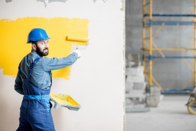 Commercial painting worker with hard hat on and roller