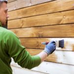 Fence Staining worker with paint brush.