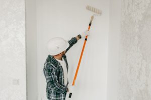 Residential painter of an interior wall with roller and hard hat on
